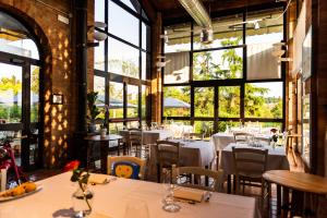 a restaurant with white tables and chairs and windows at Tenuta MONVILLONE Country House & Restaurant in Cereseto