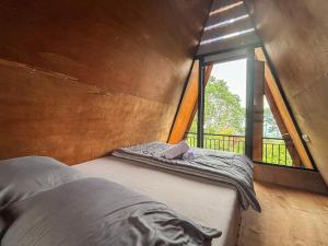 a bed in a small room with a window at Sanda Eco Cabins by AGATA in Padangan +25 photos