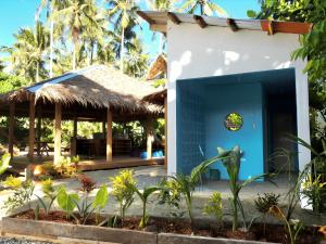 a building with a blue door and palm trees at Three Little Birds Surf Hostel in General Luna