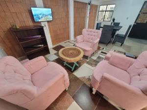 ein Wohnzimmer mit rosa Stühlen und einem Tisch in der Unterkunft Dpto Cómodo Barrio Guadalupe Céntrico con Estac y FREE WIFI in San Cristóbal de las Casas