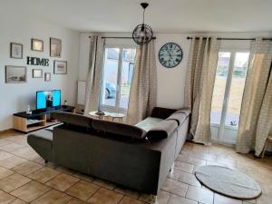 a living room with a couch and a clock on the wall at Chez Juline charmante maison de plain pied à la campagne et au calme in Bourg-Fidèle