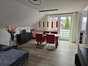 a living room with a dining table and red chairs at Wohlfuehloase24 in Gütersloh +11 photos