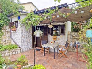 a patio with a table and chairs and an umbrella at Nives Garden house in Nerezine