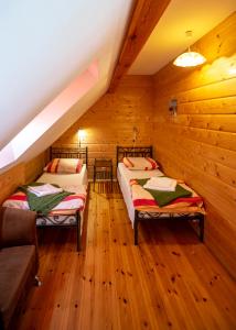 Dos camas en una habitación con paredes de madera. en Apartamenty Mewa, en Jantar