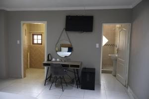 a room with a desk and a mirror and a bathroom at Boksburg Hotel in Boksburg