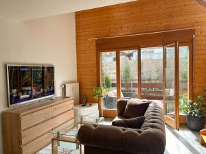 un salon avec un canapé et une télévision à écran plat dans l'établissement Duplex lumineux avec vue, à Vionnaz