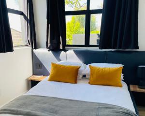 Una cama con dos almohadas amarillas frente a una ventana. en Cape20 - Luxury Villa Stay, en Ciudad del Cabo