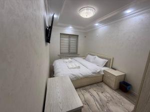 une petite chambre avec un lit et une table dans l'établissement Rusmir Apartment, à Samarcande
