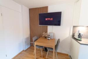 einen Esstisch mit Stühlen und einen TV an der Wand in der Unterkunft Zentrales Apartment mit Balkon direkt am Wanderweg - Alpenperle Tegernsee in Tegernsee