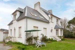 a white house with a table and an umbrella at Maison familiale côté rivière in Audierne