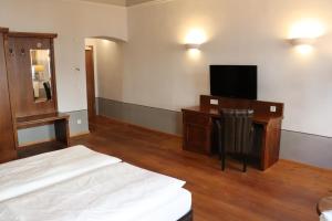 a bedroom with a bed and a desk with a television at Hotel Paul Otto in Görlitz