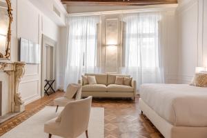 a white bedroom with a bed and a couch at La Casa di Liszt - Luxury Suites in Florence