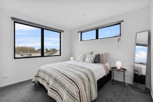 a white bedroom with a bed and two windows at Charming 2-Bedroom Townhouse in Christchurch