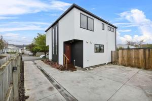 a white house with a black door and a fence at Charming 2-Bedroom Townhouse in Christchurch