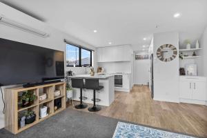 a kitchen with white cabinets and a large television at Charming 2-Bedroom Townhouse in Christchurch