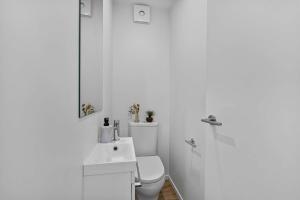 a white bathroom with a toilet and a sink at Charming 2-Bedroom Townhouse in Christchurch +5 photos