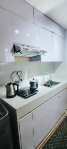 eine Küche mit weißen Schränken und einem Herd mit Backofen in der Unterkunft Morena Suite,Staycation,WiFi,Netflix,Near DLSU & Malls in Dasmariñas
