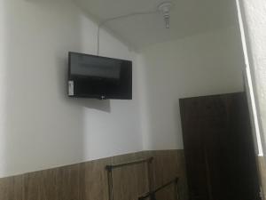 TV de pantalla plana en la pared de una habitación en Pousada Tilu, en Aparecida