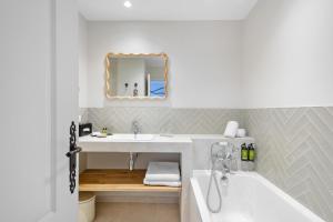 a bathroom with a sink and a tub and a mirror at Hôtel La Villa Sainte Valérie Adults Only in Juan-les-Pins