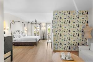 a bedroom with a bed and a couch and a table at Hôtel La Villa Sainte Valérie Adults Only in Juan-les-Pins
