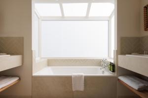 a bathroom with a bath tub under a window at Hôtel La Villa Sainte Valérie Adults Only in Juan-les-Pins