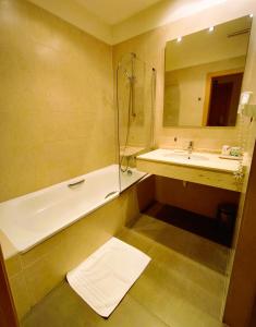 Un baño con bañera, lavabo y espejo. en Hotel Villa Marcilla, en Marcilla 37 fotos más