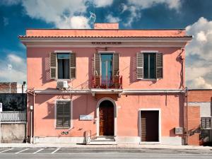 un edificio rosa con balcone su una strada di Le dimore di Traiano a Civitavecchia