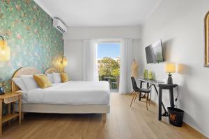 a bedroom with a bed and a desk and a window at Hôtel La Villa Sainte Valérie Adults Only in Juan-les-Pins
