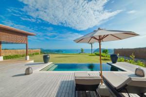a patio with an umbrella and chairs and a pool at Selong Selo Resort and Residences in Selong Belanak