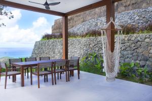 a patio with a table and chairs and a stone wall at Selong Selo Resort and Residences in Selong Belanak