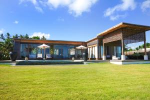 a house with a lawn in front of it at Selong Selo Resort and Residences in Selong Belanak