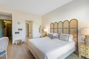 a white bedroom with a large bed and a chair at Hôtel La Villa Sainte Valérie Adults Only in Juan-les-Pins