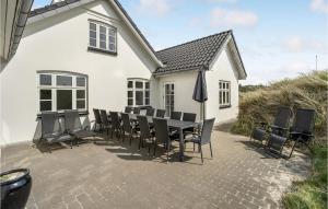 a table and chairs in front of a white house at Holiday Home Plantagevej Ringkøbing Xii in Søndervig
