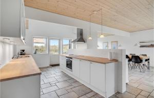 a large kitchen with white cabinets and a table at Holiday Home Plantagevej Ringkøbing Xii in Søndervig