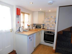 a kitchen with white cabinets and a counter top at 2 Museum Cottages in Sheringham