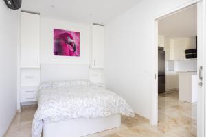 a white bedroom with a bed and a painting on the wall at Apartamento con vistas panorámicas in Puerto de la Cruz +20 photos