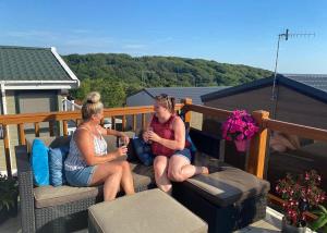 two women sitting on a deck looking at their cell phones at Shear Barn Holiday Park in Hastings