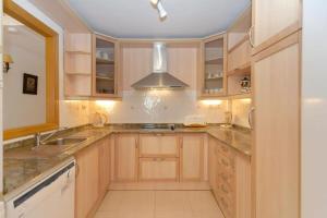 eine große Küche mit Holzschränken und einem Waschbecken in der Unterkunft La Manga Club Resort - Los Olivos 54 in Atamaría