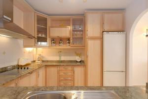 eine Küche mit Holzschränken und einem weißen Kühlschrank in der Unterkunft La Manga Club Resort - Los Olivos 54 in Atamaría