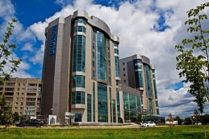 un gran edificio con ventanas de cristal en una ciudad en Dedeman Oskemen Hotel, en Öskemen