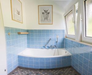baño de azulejos azules con bañera. en Bei Fuchses am Wisentpfad, en Bad Berleburg