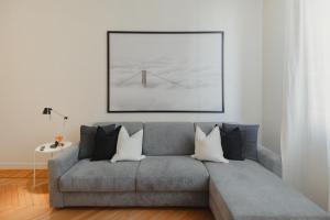 a living room with a gray couch with a painting on the wall at GoHost - Quiet, Bright & Stylish Flat in the Heart of Milan in Milan