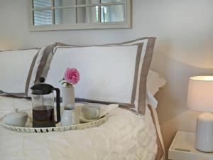 a tray with tea sets and a flower on a bed at Petit Knowle in Cuckfield