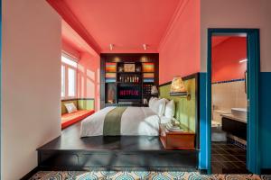 a bedroom with orange walls and a bed and a bathroom at Dakao Vibe Studios by CIRCADIAN in Ho Chi Minh City