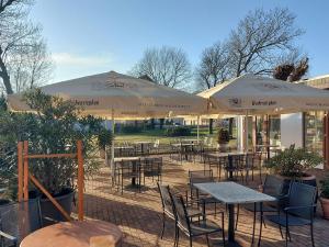 an outdoor patio with tables and chairs and umbrellas at Land-Gut-Hotel- Weisser Schwan in Zossen