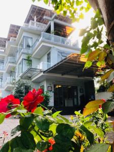 ein weißes Gebäude mit roten Blumen davor in der Unterkunft Hue Panorama Villa in Cư Chinh