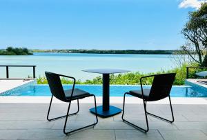 two chairs and a table with a view of the water at the 478 -pool & spa- Miyakojima Luxury Villa in Miyako Island
