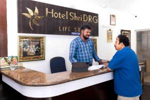 two men standing at a hotel shirmhr dipig counter at Hotel DRG Heritage in Tiruppūr +6 photos