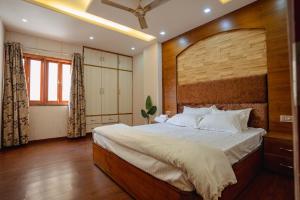 a bedroom with a large bed with a wooden headboard at The OG Stay - Luxury Apartment Ajmer in Ajmer