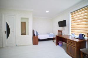 a bedroom with a bed and a desk with a telephone at Hotel Shaboda in Samarkand